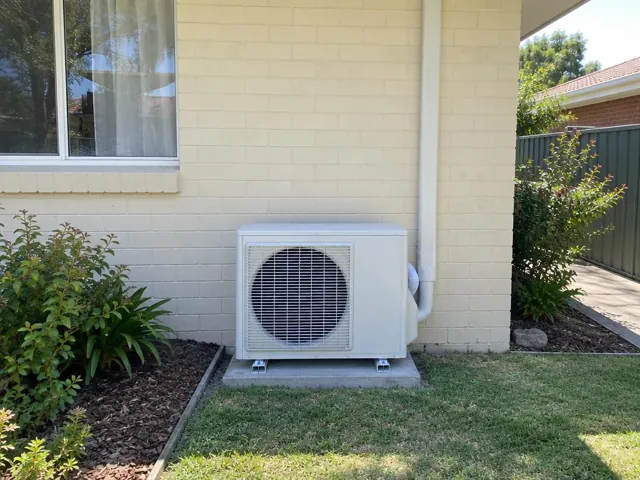 Outdoor air conditioner unit on a concrete pad beside a brick house wall in Elizabeth