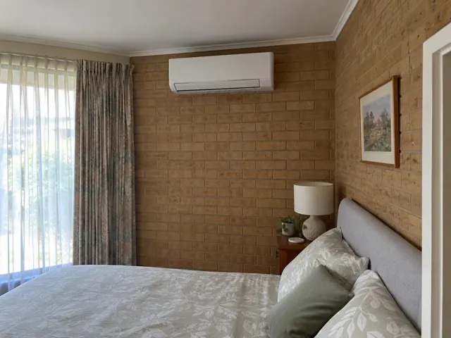 Split system indoor unit on a brick bedroom wall above a bed in Elizabeth Park